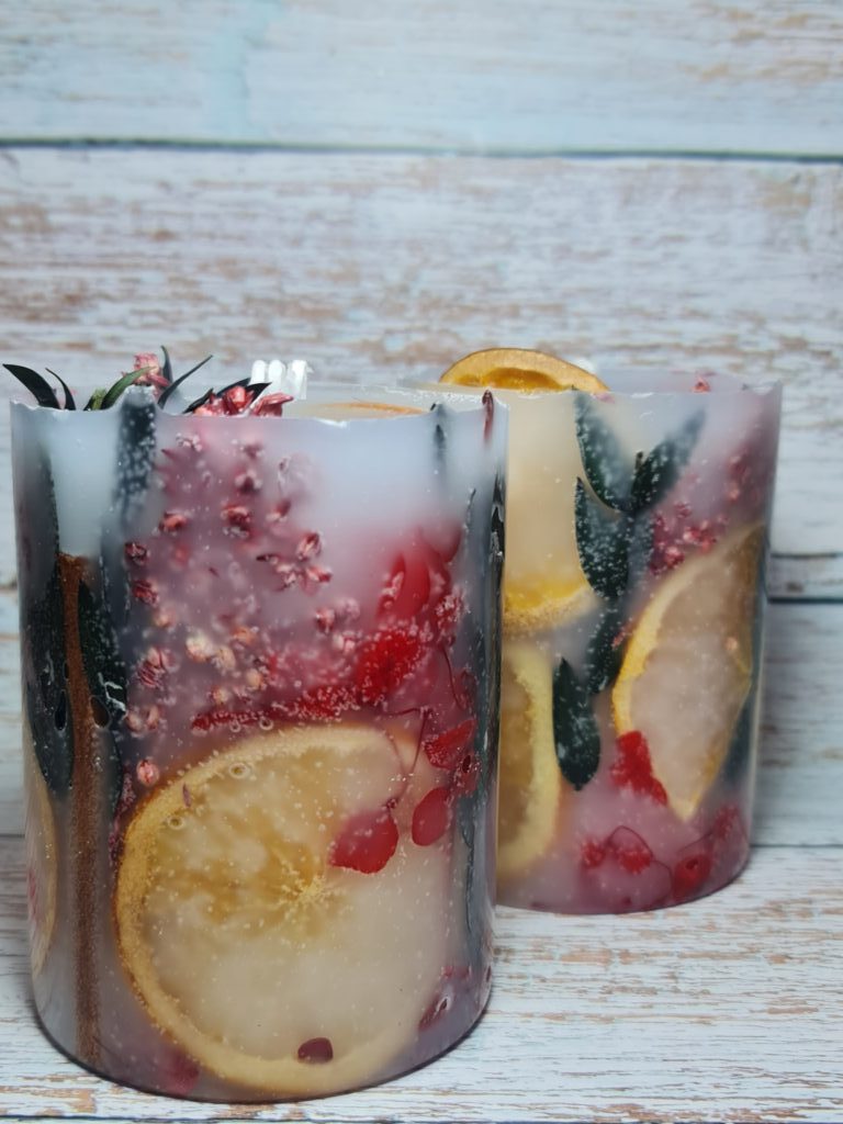 Свеча цветы за стеклом с апельсинами.