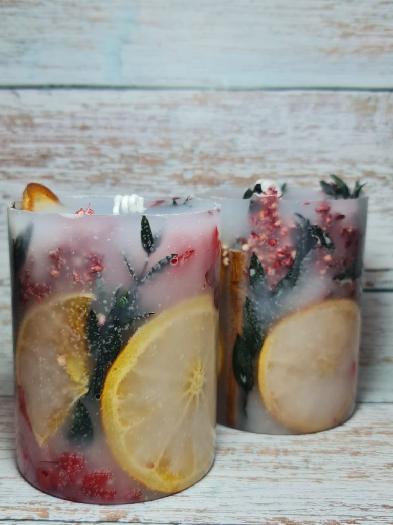 Свеча цветы за стеклом с апельсинами.